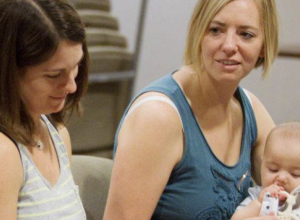 Deux femmes et un bébé dans une salle.