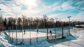 Patinoire de hockey avec bandes dans des conditions hivernales, avec 4 joueurs.