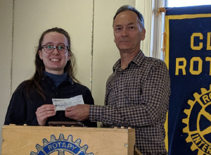 Deux personnes tenant un chèque avec une bannière arborant le logo du Club Rotary à côté d'eux.