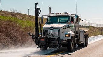 Camion effectuant le nettoyage d'une rue avec un jet d'eau.