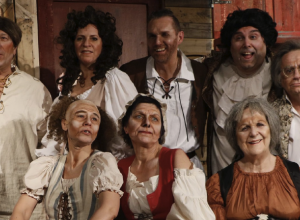 Huit personnes costumées avec un style de l'ancien temps faisant face à la caméra.